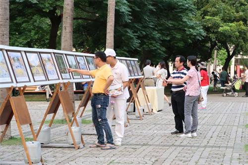 '图10~11:路过的民众驻足在展板面前了解法轮功真相。'