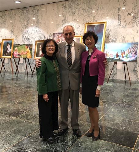 '图2:纽约州133区众议员Joe?Errigo(中)支持法轮功学员反迫害。他与美展讲解员在美展作品前合影。'