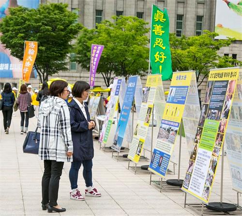 '图10:2018年5月13日,首尔市中心广场举行5·13“世界法轮大法日”庆典,路人驻足观看展板。'