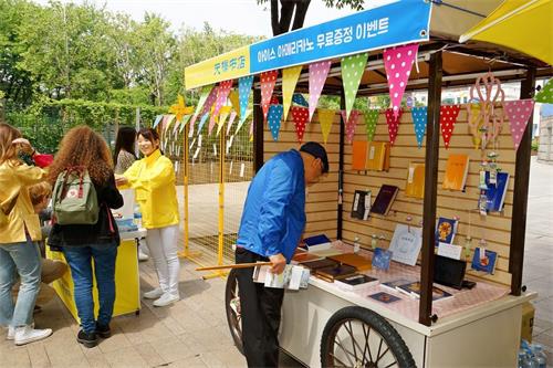 '图11:接受真相传单的市民来到天梯书店展位前饶有兴趣地了解有关法轮功修炼的书籍。'