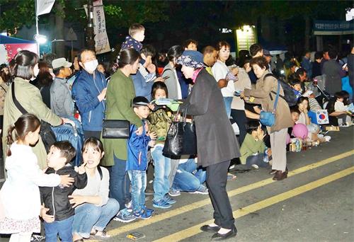 '图4:观众纷纷接过法轮大法传单,认真阅读'