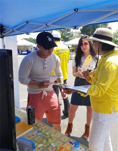 '图3:游客在法轮功展位前驻足听真相'