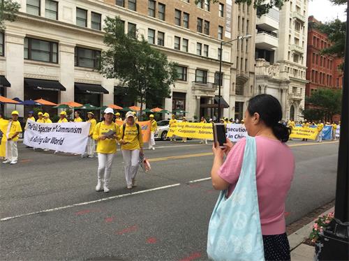 '图1:大陆华人给法轮功学员游行队伍拍照。'