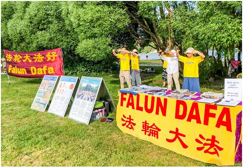 图1:学员在摊位竖起“法轮大法好”的横幅、摆上真相展板信息台并演示法轮功的五套功法,将法轮功的美好带给当地的社区民众。
