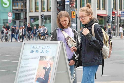 '图5:波兰女孩在展板前仔细阅读,感到中共对法轮功学员的迫害触目惊心。'