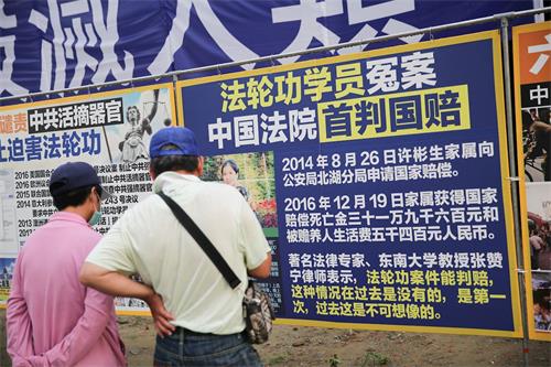 '图11:来自台南西港的市民郭先生夫妇第一次遇到法轮功,沿着真相展板一片片非常仔细的阅读着,并呼吁公安明智抉择。'