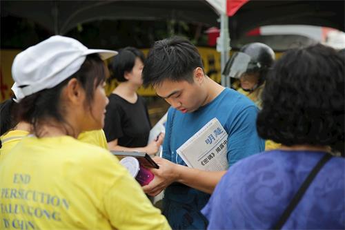 '图12:刚来台湾工作两个月的越南翻译工作者武先生(中),拿到台南的炼功点资讯很感动。'