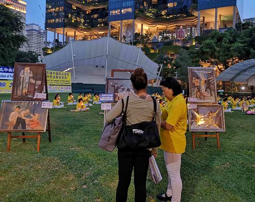 图6~9:新加坡芳林公园里,游客们驻足听法轮功学员讲真相