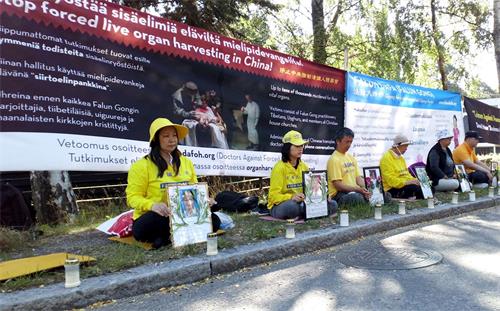 '图1:法轮功学员在芬兰中使馆旁静坐,抗议中共十九年来对法轮功学员的残酷迫害'