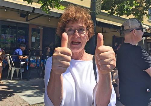 图19:看到法轮功学员的队伍,来自德国的玛莱琳纳(Mrienne)不太会说英文,竖起两个拇指夸赞。学员告诉她,在德国也有很多人修炼法轮功,法轮大法的网站有德语的介绍。她非常高兴,用力点头。