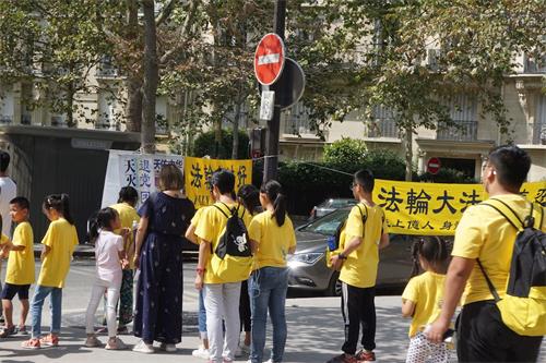 '图3:一队大陆来的学生旅游团正在等红灯时观看真相展板'