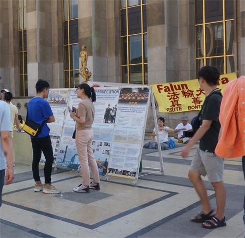 '图8:到德国留学的中国留学生(身着蓝色T恤)和法轮功学员交谈'
