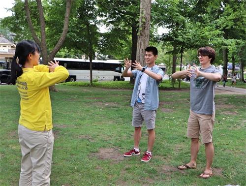 '图14:来自波士顿的大学生柯尔(Cole右)和克里斯(Chris左)正在学炼法轮功功法动作。'