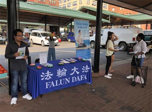 '图:明州法轮功学员在当地的农贸市场设置展位,介绍功法'