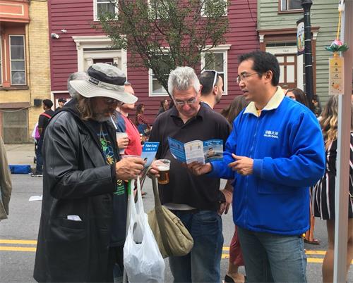 '图2~3:法轮功学员在纽约州府奥伯尼云雀节上向人们介绍功法,讲述发生在中国的迫害事实。'