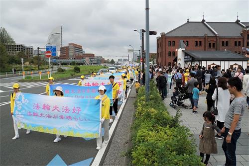 '图6:法轮功学员的游行队伍经过著名景点横滨红砖房,游客纷纷拍照'