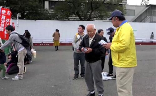 '图5:也有的民众接过介绍法轮功的资料,听完学员讲解后表示很有兴趣学炼功法。'