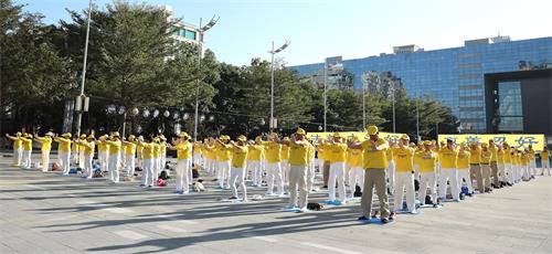'图2~7:二零一九年十二月十四,大台中地区的法轮功学员在市政府广场上集体炼功。悠扬炼功乐声响起,学员展示五套功法缓、慢、圆的整齐动作,殊胜祥和的壮观场面,吸引过往行人的目光。'