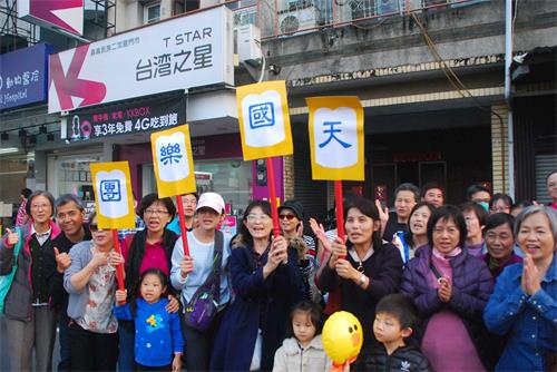 '图7: 一群嘉义市民在民族路上兴奋的举着写着“天国乐团”的广告牌欢迎天国乐团。'