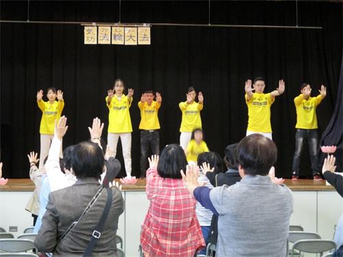 '图1:观众认真的一起和台上的法轮功学员们学炼。'