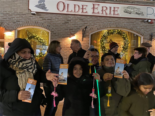 '图4:当法轮大法游行队伍走过来时,人们纷纷接过法轮功学员送与的传单与小莲花'