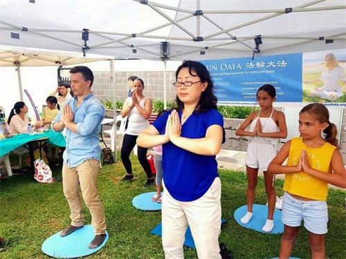 '图3:法轮功学员在展位上教民众学炼法轮功五套功法'