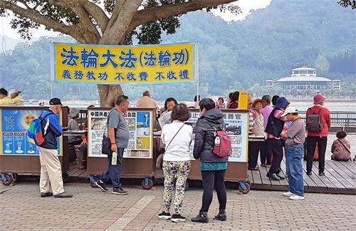 '图2:游客仔细观看真相展板,有的直接打开中国新闻观看。'