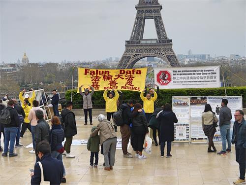 '图1:三月二十四日下午,人权广场人流不断,法轮功学员在巴黎的人权广场进行炼功和讲真相的活动。人们被法轮功学员安静、祥和的炼功吸引,不少游客驻足了解真相。'