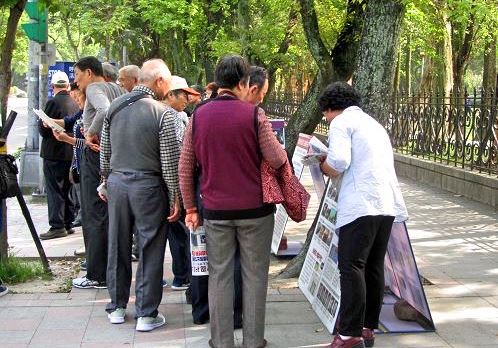 '图11:中国游客听法轮功学员讲真相。'