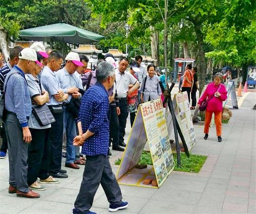 '图2:中国大陆游客一批一批的在真相展板前驻足'