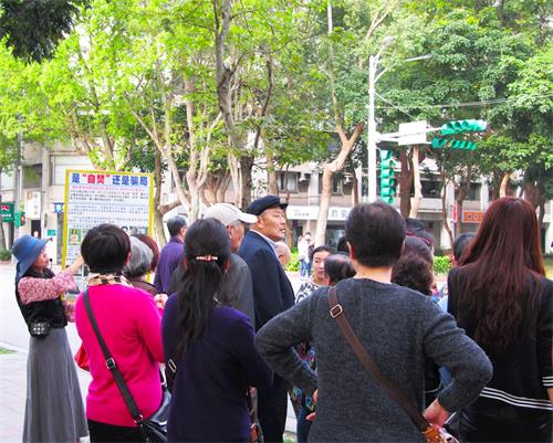 '图3:中国大陆游客眼观展板、耳听法轮功学员讲真相。'