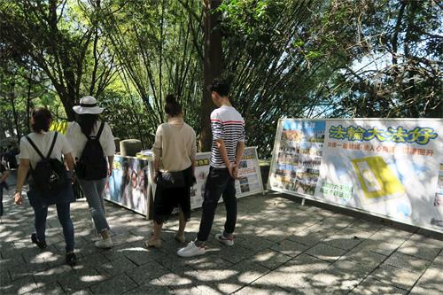 '图3~4:青龙步道上,大陆游客停下脚步,关注法轮功真相。'