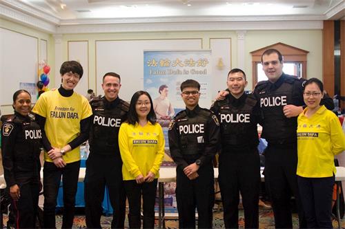 '图1:约克区警察驻足法轮功真相展位并和学员们合影'