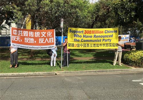 '图1~2:法轮功学员在华人聚集区展示法轮功和平反迫害的信息'