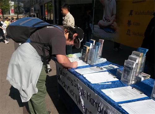 '图2:一位路人签署了制止迫害的请愿书'