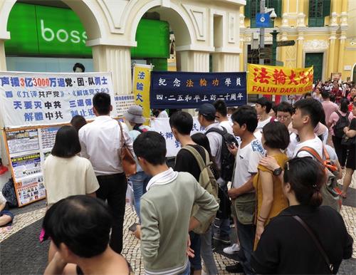 '图1~2:澳门学员4.25集会现场吸引人山人海的游客驻足观看'