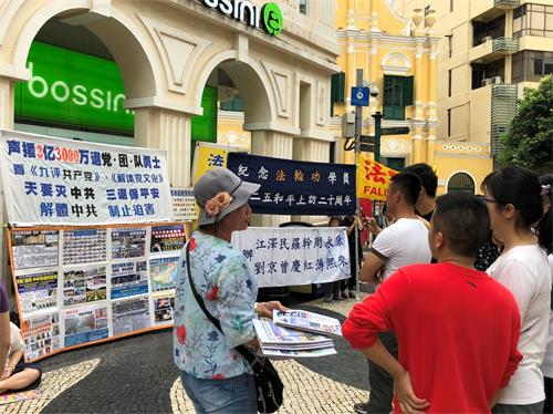 '图6:游客听法轮功学员讲真相'
