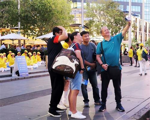 '图5:悉尼过路民众学炼法轮功功法和拍照留念'