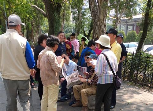 图4:法轮功学员向中国大陆游客讲真相,也是景点上的指路灯、方向塔。