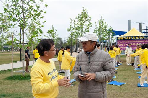 '图3:法轮功学员在向越南裔居民楚先生(Loc Chu)在向民众介绍法轮功功法。'