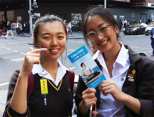 '图13:韩国女孩珍妮特·金(左)和阿什利·颂得到莲花并议论着:我们很高兴今天让我们幸遇这么好的一幕(法轮功游行)'