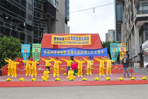 '图1:二零一九年五月十二日,墨尔本法轮功学员在市中心女王桥广场(Queensbridge Square)举行隆重庆典,恭贺第二十届“世界法轮大法日”和创始人李洪志先生华诞。图为学员们在展示功法。'