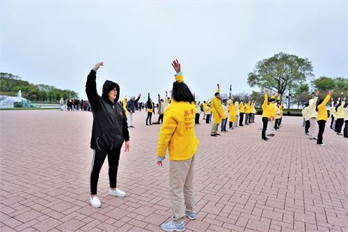 '图8:来自明尼阿波利斯的Julie则当场跟法轮功学员学起了炼功动作。'