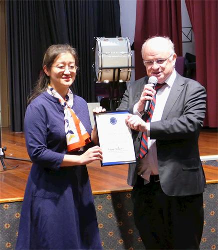 '图2:二零一九年五月三日,悉尼帕拉马塔市(City of Parramatta)市长威尔森(右)向澳洲法轮大法佛学会会长赵博士颁发了褒奖令,表彰法轮大法为当地社区所作出的贡献,并祝贺法轮大法弘传世界27周年。'