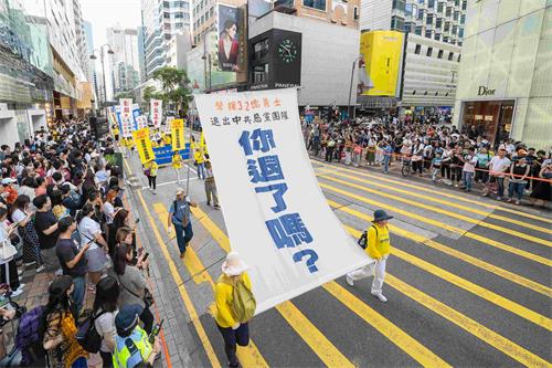 '图11:法轮功学员举起大型幡旗,呼吁大陆民众退出中共党团队。'