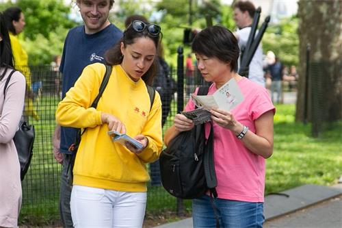 '图1~6:法轮功学员纽约炮台公园(Battery Park)拉起大型讲真相横幅,并向游客讲真相,人们驻足观看法轮功学员集体炼功'