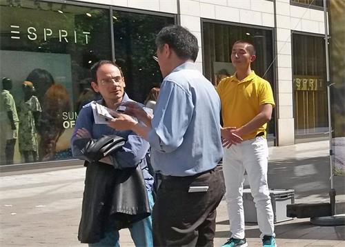 '图8:这位先生(左)想要学习法轮功,当地学员给了他汉堡法轮功学员炼功点的名片。'