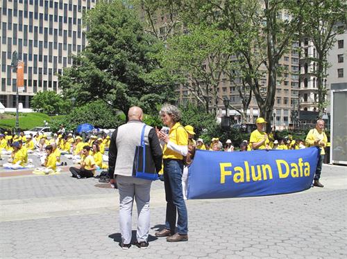 '图2:国际金融服务公司(WFG)保险代理人 贾维尔·维加(Javier Vega)在富利广场(Foley Square)遇到正在集体炼功的法轮功学员,一位德国法轮功学员给他讲真相'