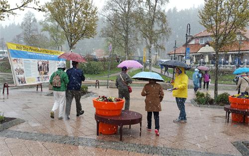 图1: 在风雪中,德国法轮功学员Yansi对大陆游客用中文说:中国人,德国欢迎你们,请记住法轮大法好!
