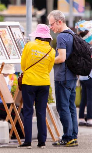 '图11:从瑞士来台旅游的 丹尼先生(Danny,右)观看图片展,透过学员的解说,明白了些大法洪传的情况。'